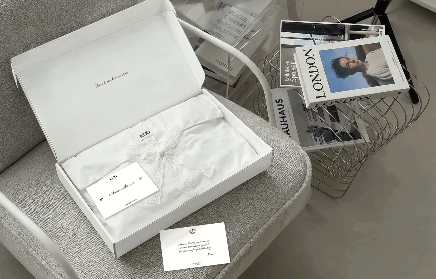 The opened white KUG mailer box with tissue, a lace ribbon and a handwritten card
